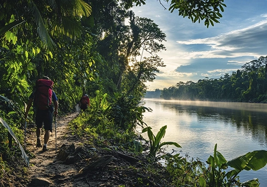 Iquitos night jungle tour — adventurers with headlamps spotting caimans along the riverbank during a nocturnal Amazon expedition